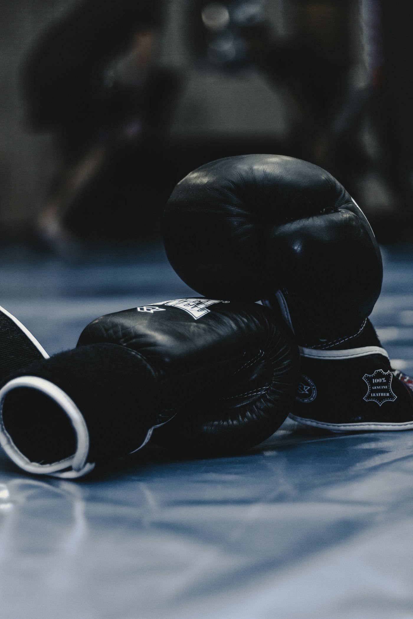 Black boxing gloves resting on a gym mat